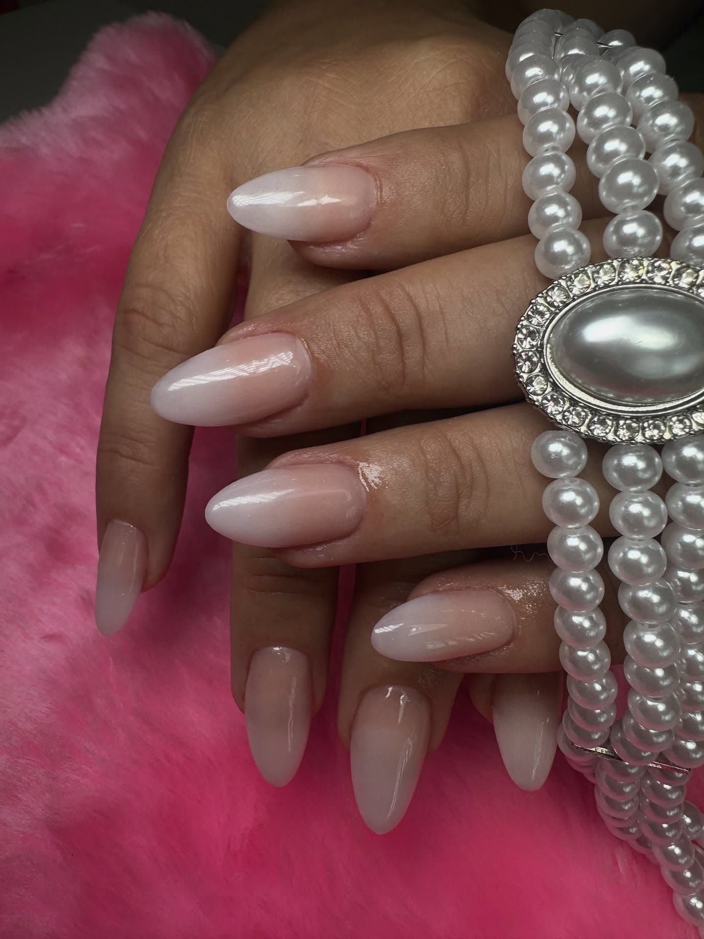 Nude almond nails adorned with individual pearls on each finger