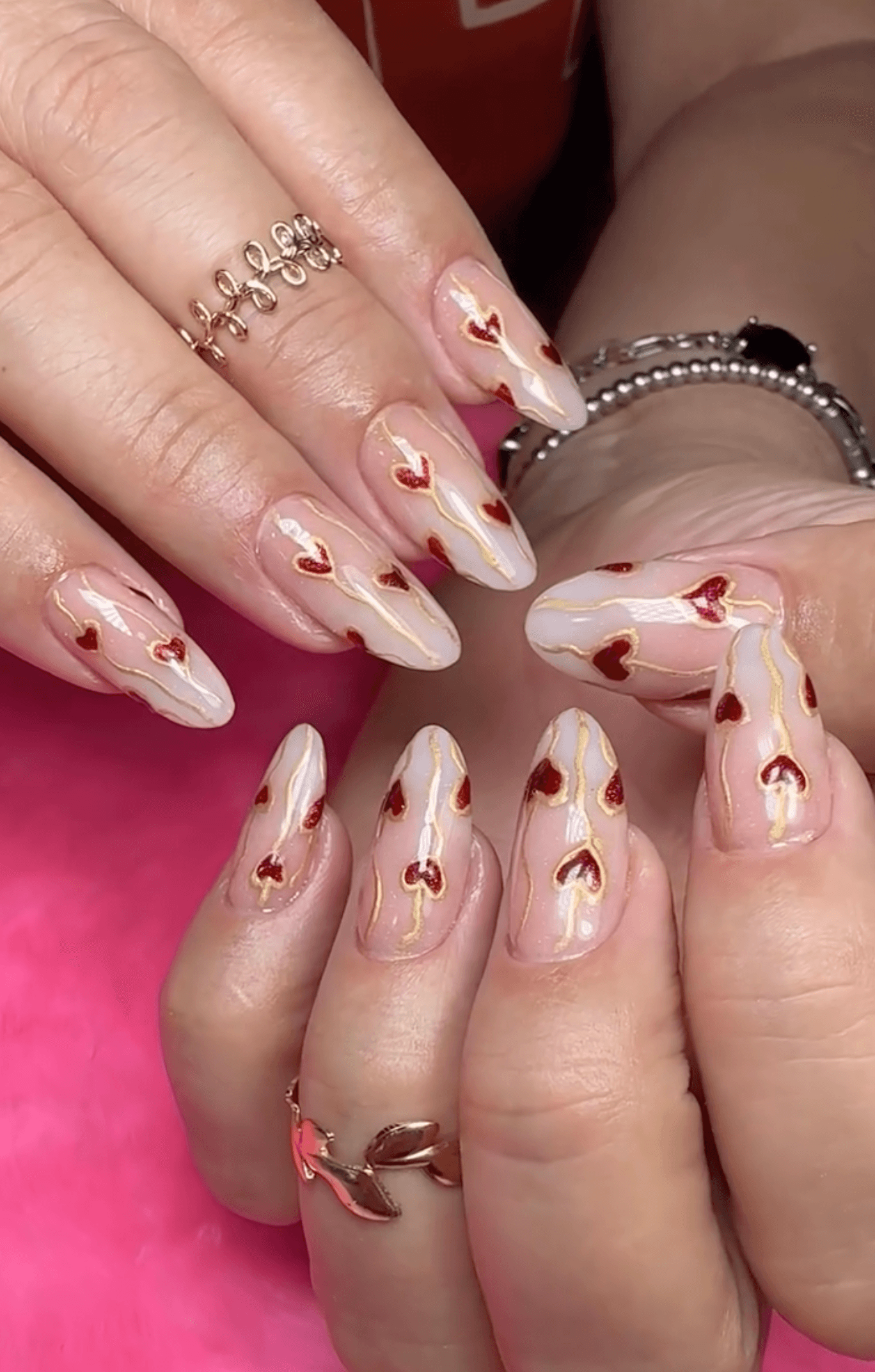 Nude nails with red hearts and gold foil in an artistic layout