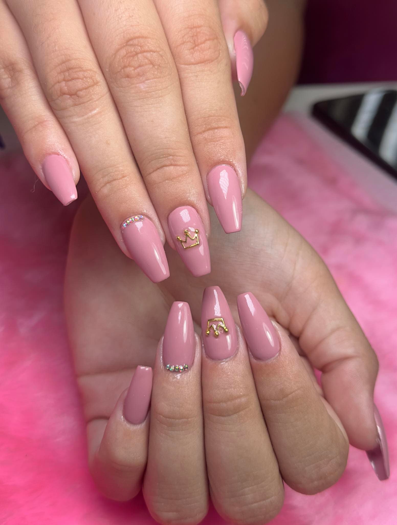 Pink acrylic nails with a jewelled crown on the centre accent nail