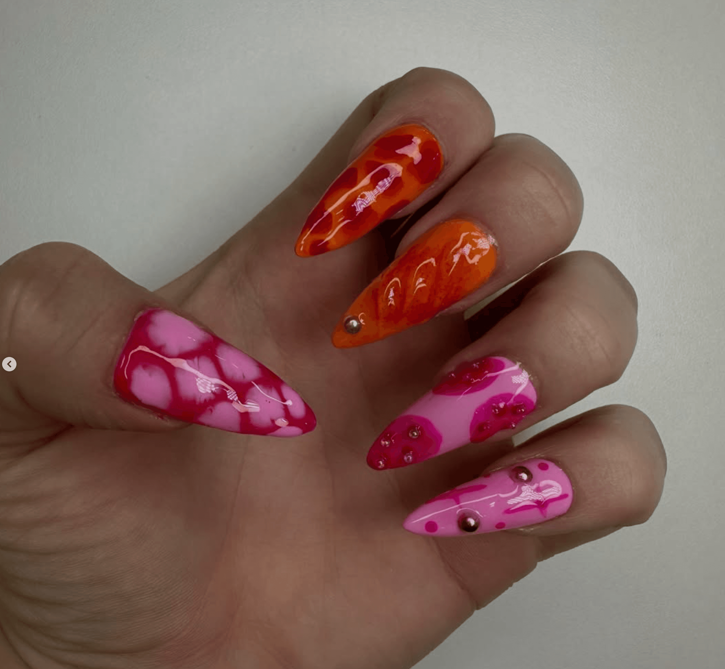 Abstract nail art in pink and orange with multicolour rhinestones