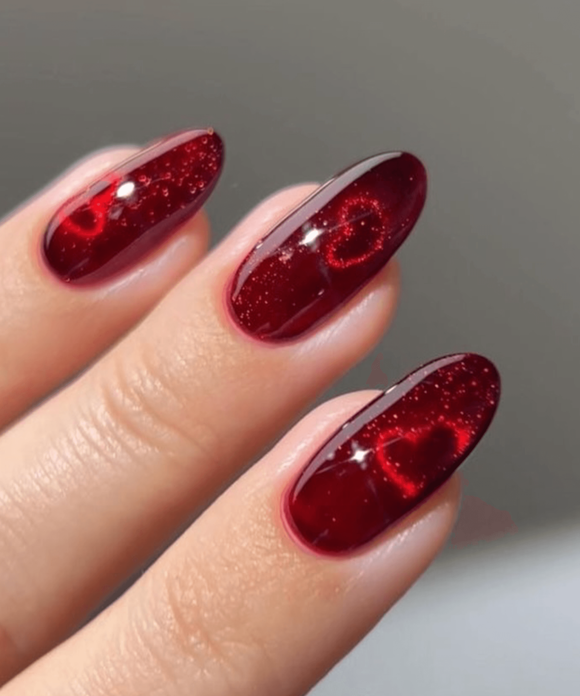 Red almond nails with chrome cat-eye and fine glitter in the base